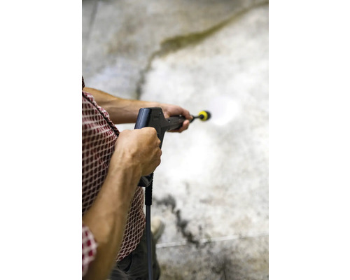 En person använder en högtryckstvätt för att rengöra en yta.