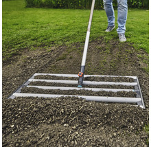 Jordbearbetning med en avjämningsskena i trädgården.