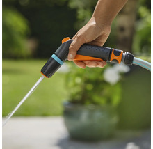 En hand håller i en Gardena trädgårdsspruta som det kommer vatten ur.
