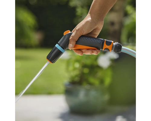 En hand håller i en Gardena trädgårdsspruta som det kommer vatten ur.