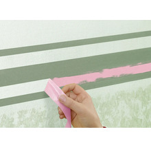 En person tar bort tejp från en vägg med målade ränder.