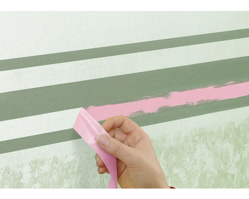 En person tar bort tejp från en vägg med målade ränder.