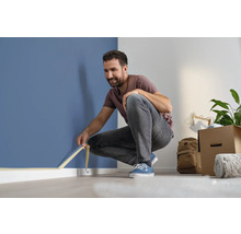 Man fäster maskeringstejp på en vägg