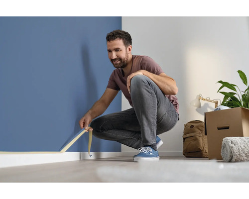 Man fäster maskeringstejp på en vägg