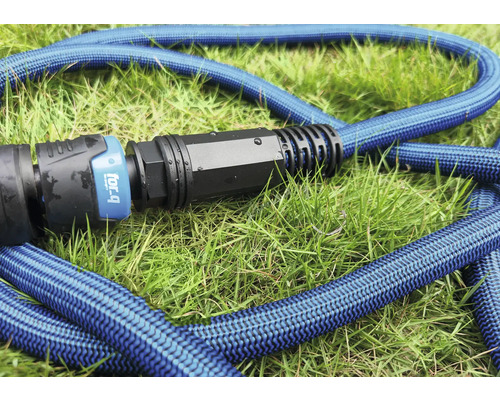Blå flexibel trädgårdsslang med koppling på gräs