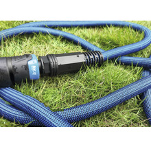 Blå trädgårdsslang med koppling på gräs