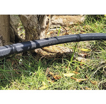 Bevattningsslang i trädgården med läckande vatten