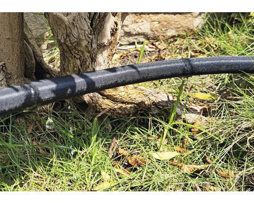 Bevattningsslang i trädgården med läckande vatten