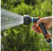 En hand håller en trädgårdsspruta som vatten kommer ut ur.