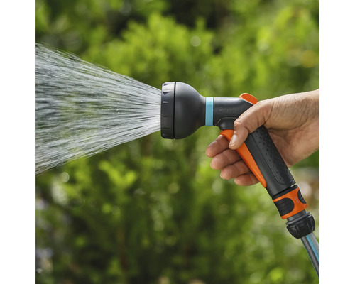 En hand håller en trädgårdsspruta som vatten kommer ut ur.