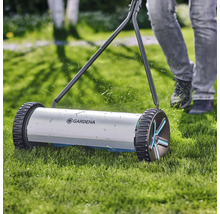 Handgräsklippare i drift på gräsmatta med Gardena-logotyp