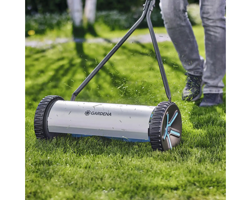 Handgräsklippare i drift på gräsmatta med Gardena-logotyp