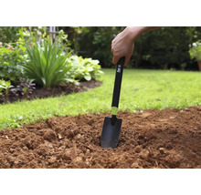 Trädgårdsarbete med en handspade i trädgårdslandet