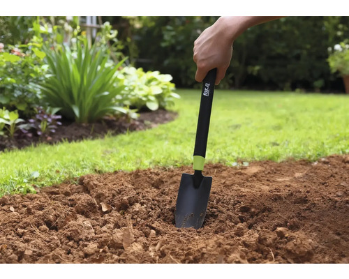 Trädgårdsarbete med en handspade i trädgårdslandet