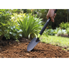 Person använder en trädgårdsspade i en rabatt.