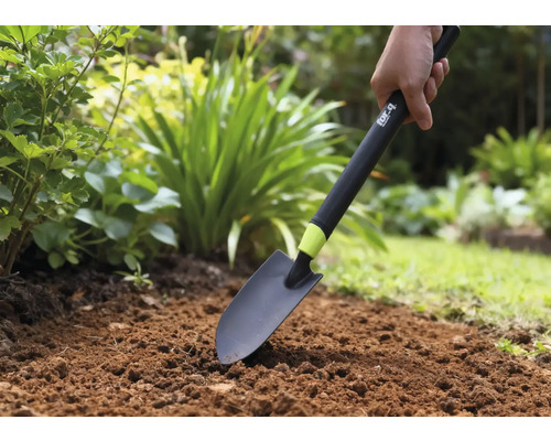 Person använder en trädgårdsspade i en rabatt.