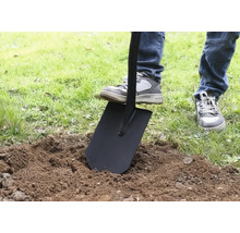 En person sticker ner en spade i jorden.