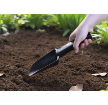 En person använder en handspade i trädgården.