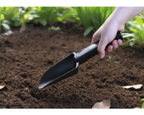 En person använder en handspade i trädgården.