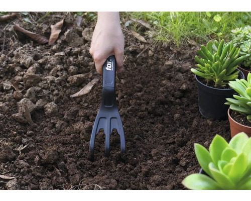 Trädgårdsarbete med en trädgårdskratta i jorden