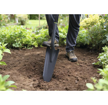 Person använder en spade för att gräva i trädgården.