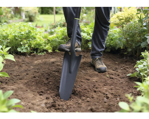 Person använder en spade för att gräva i trädgården.