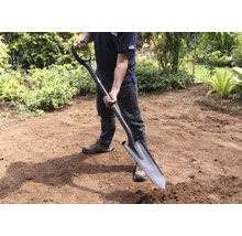 Man håller en spade i trädgården.