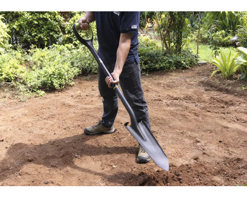 Man håller en spade i trädgården.