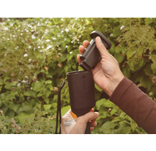 Person sätter in batteri i ett trädgårdsredskap.