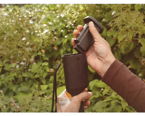 Person sätter in batteri i ett trädgårdsredskap.