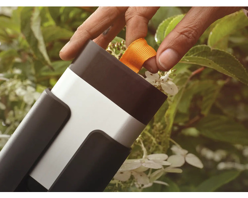 Person drar i ett orange band på ett trädgårdsredskap.