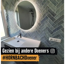 Badrum med handfat, spegel och väggplattor i fiskbensmönster