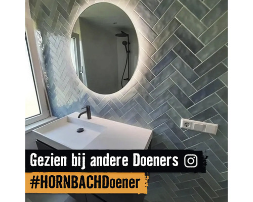 Badrum med handfat, spegel och väggplattor i fiskbensmönster