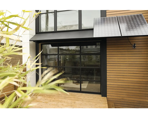Utsida av ett hus med solpaneler och garageport i glas