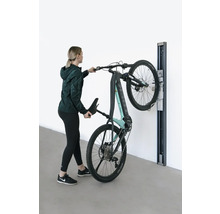 Kvinna hänger upp en elektrisk mountainbike på ett väggfäste.