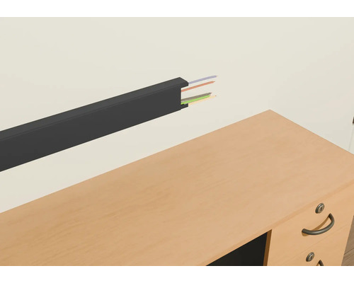 Kabelskydd av plast med kablar på en vägg ovanför ett skrivbord