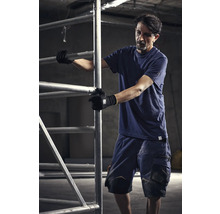 Man i arbetskläder som arbetar med en byggnadsställning.