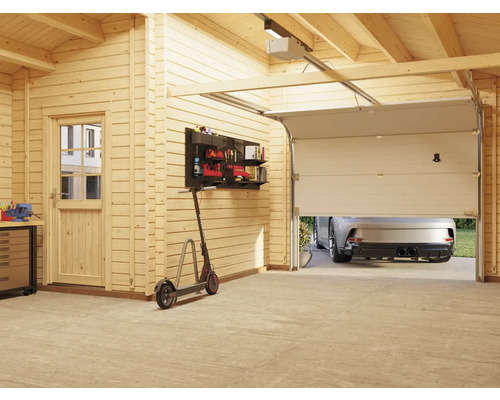 Interiör av ett garage med träpanel, garageport, verktygsvägg och en bil i bakgrunden