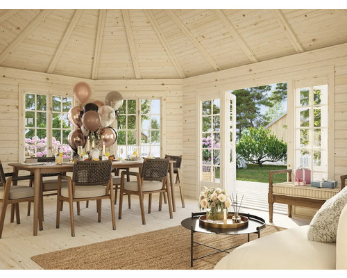 Ljust trähus med matbord, stolar, dekoration och öppna fönster mot trädgården.