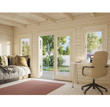 Interiör av ett trädgårdshus i trä med säng, skrivbord och utsikt över trädgården