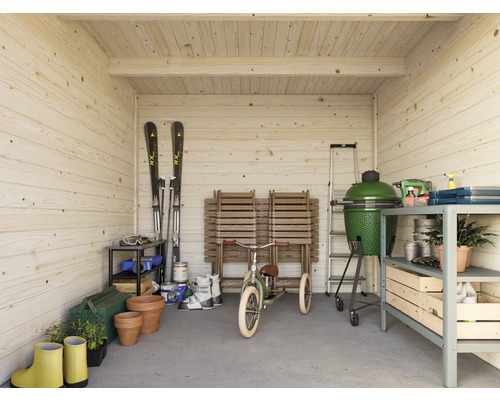 Interiörbild av ett trähus med trädgårdsredskap, grill och skidutrustning
