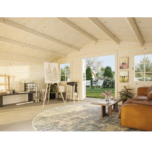 Ljus trädgårdshusinteriör med ateljéområde, soffa och utsikt över trädgården