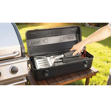 Grillbestickset i en svart förvaringslåda bredvid en grill