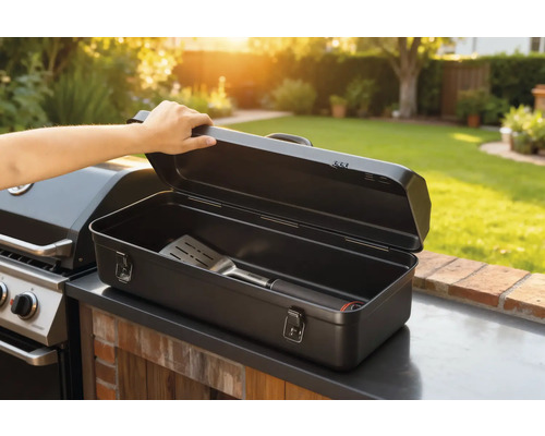 Öppen grillbesticklåda med stekspade bredvid grill i trädgården.