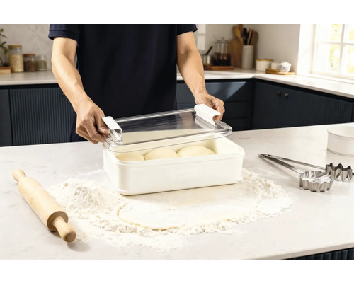 Scen i ett kök: en man öppnar en förvaringslåda med deg, omgiven av mjöl, en kavel och kakformar.