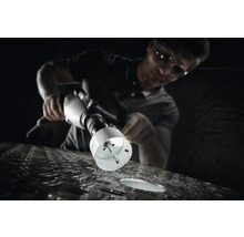 En man borrar ett hål i en metallyta med en hålsåg.