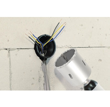 Vägg med borrhål, elektriska kablar och en hålsåg.