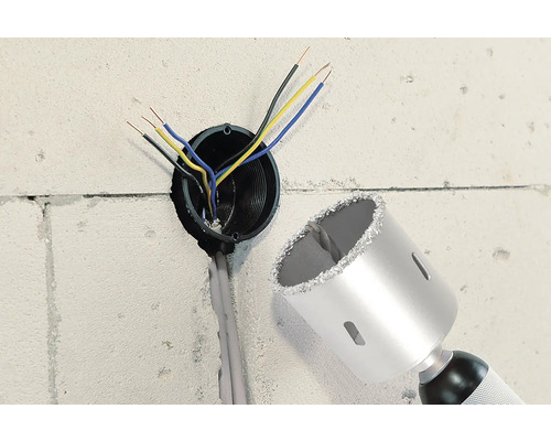 Vägg med borrhål, elektriska kablar och en hålsåg.