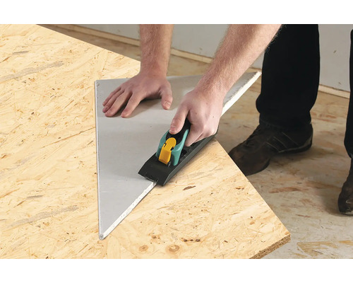 Användare bearbetar gipsskiva med kantfräs på en träskiva