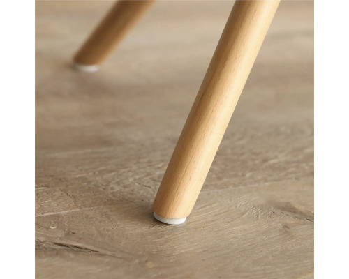 Detaljbild av ett möbelben i trä med golvskydd.